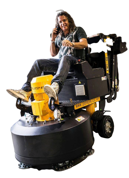 A man is sitting on a machine talking on a cell phone.