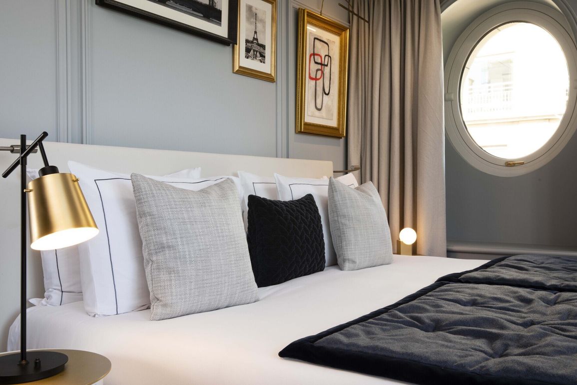 Une chambre avec un lit, une lampe et une fenêtre ronde.