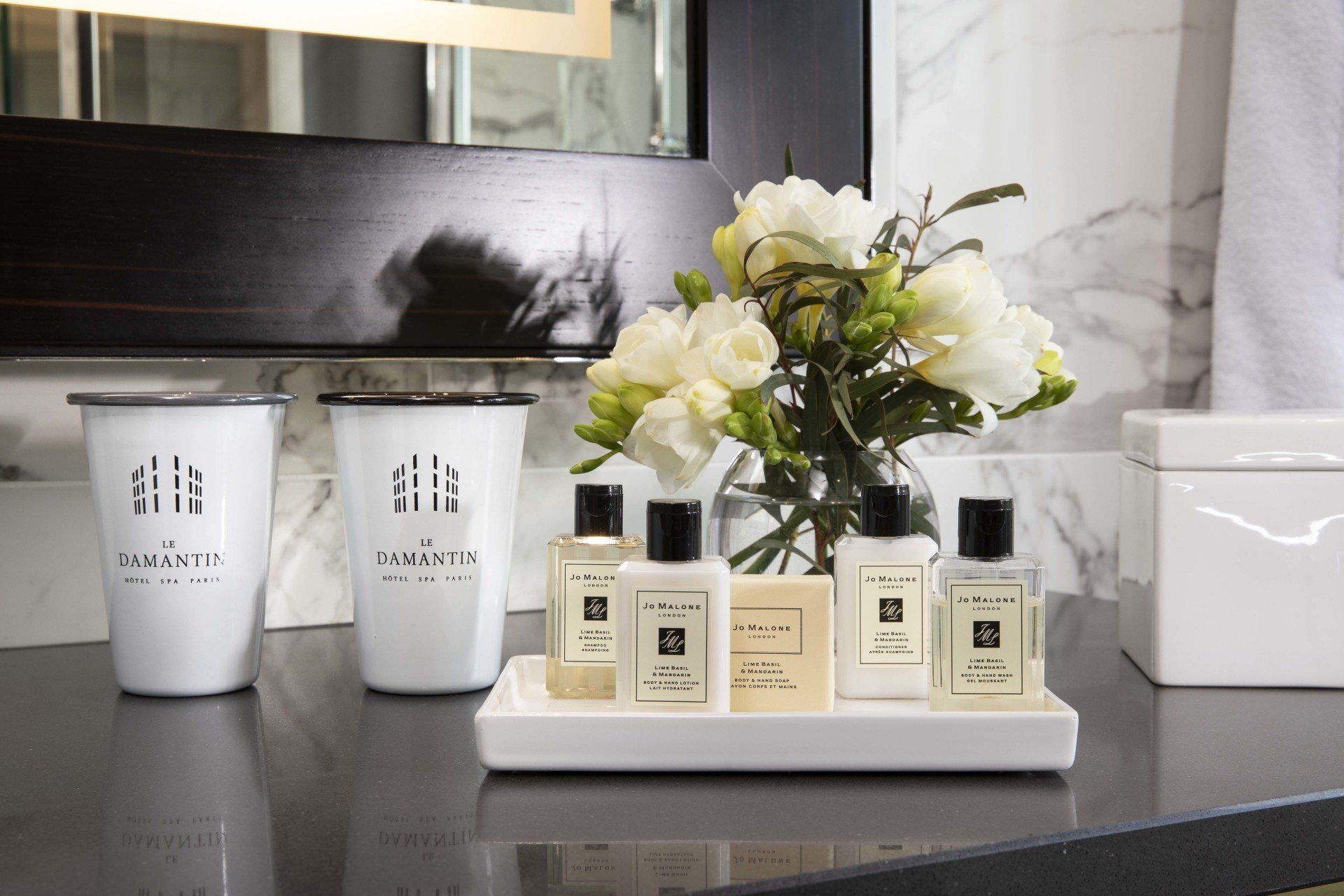 Un comptoir de salle de bain avec un plateau de produits de toilette et un vase de fleurs.