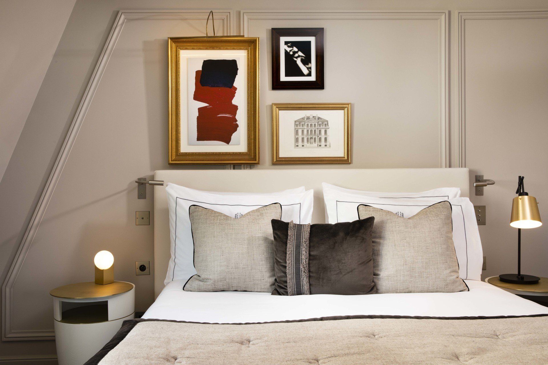 Une chambre avec un lit, une table de nuit, une lampe et des tableaux au mur.