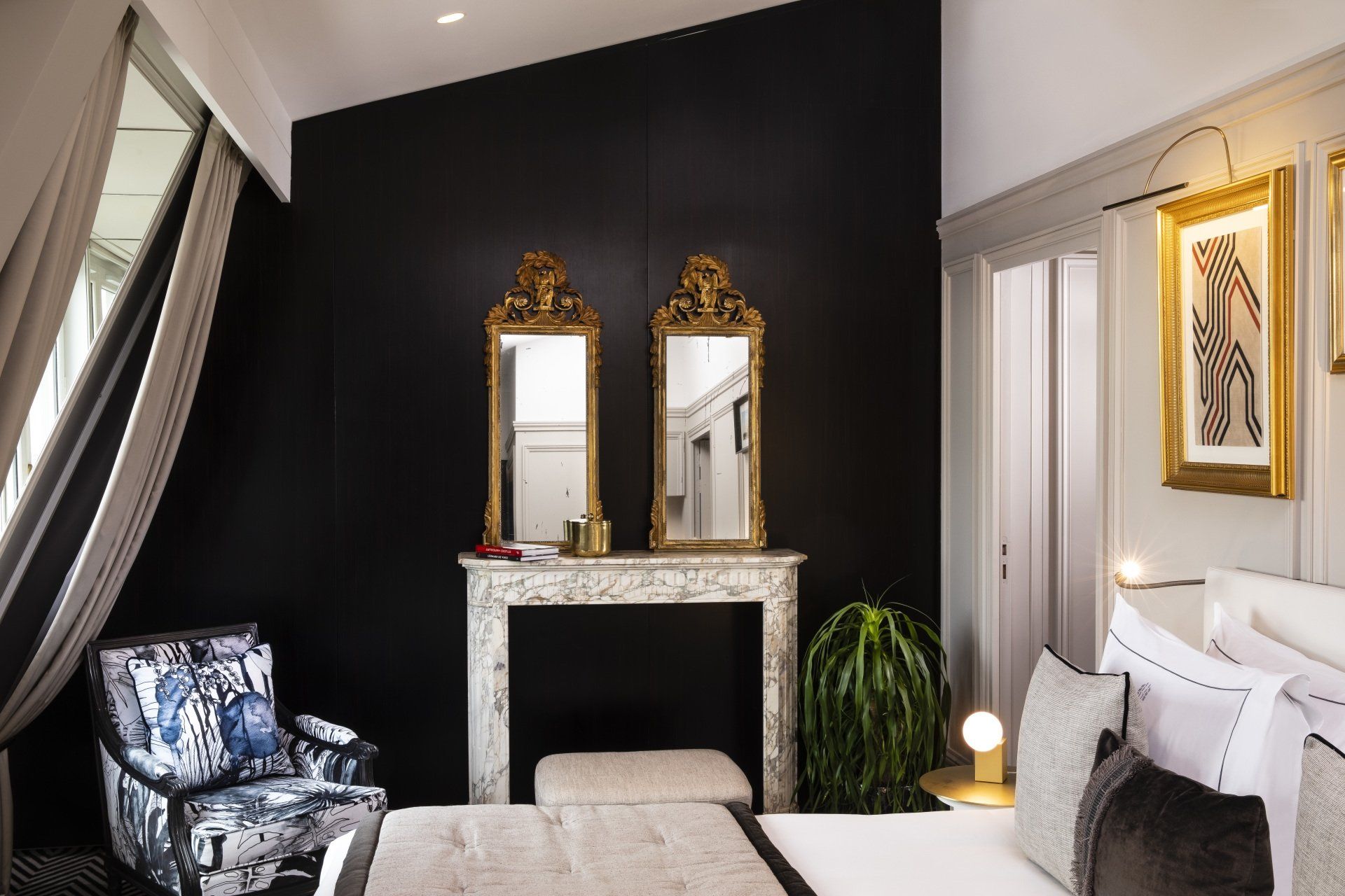 Une chambre avec un lit, une chaise, deux miroirs et une cheminée.