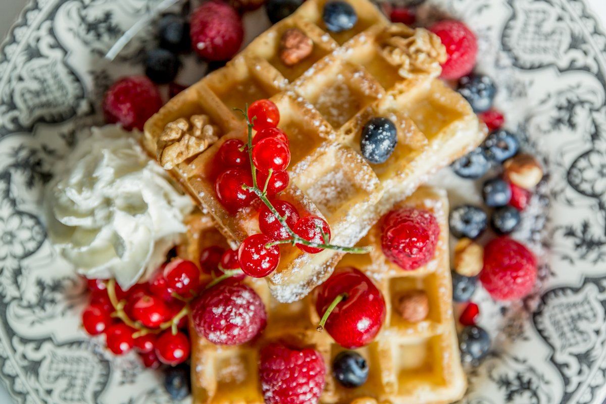 Deux gaufres avec de la crème fouettée et des baies sur une assiette.