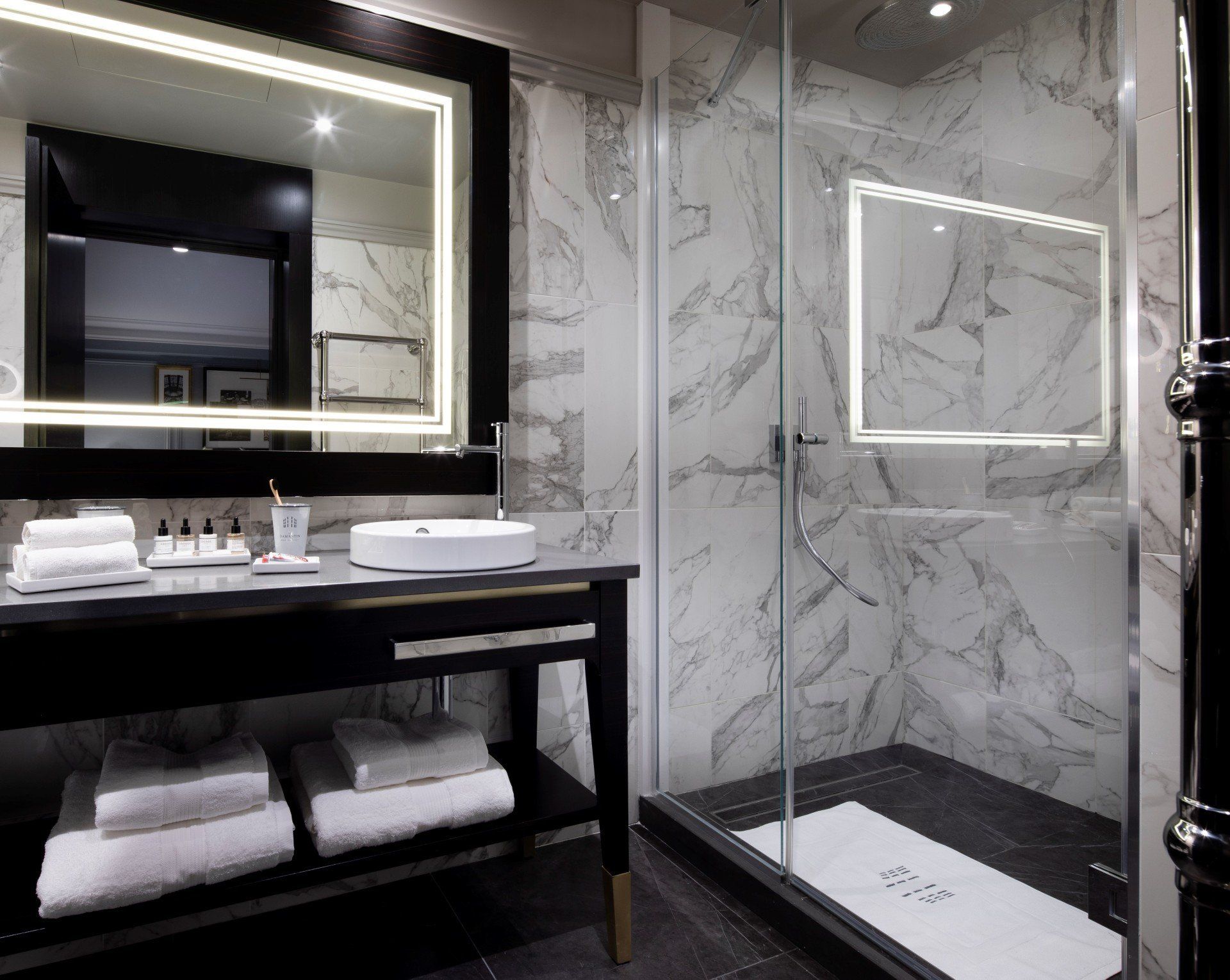 Une salle de bain avec lavabo, miroir et douche à l'italienne