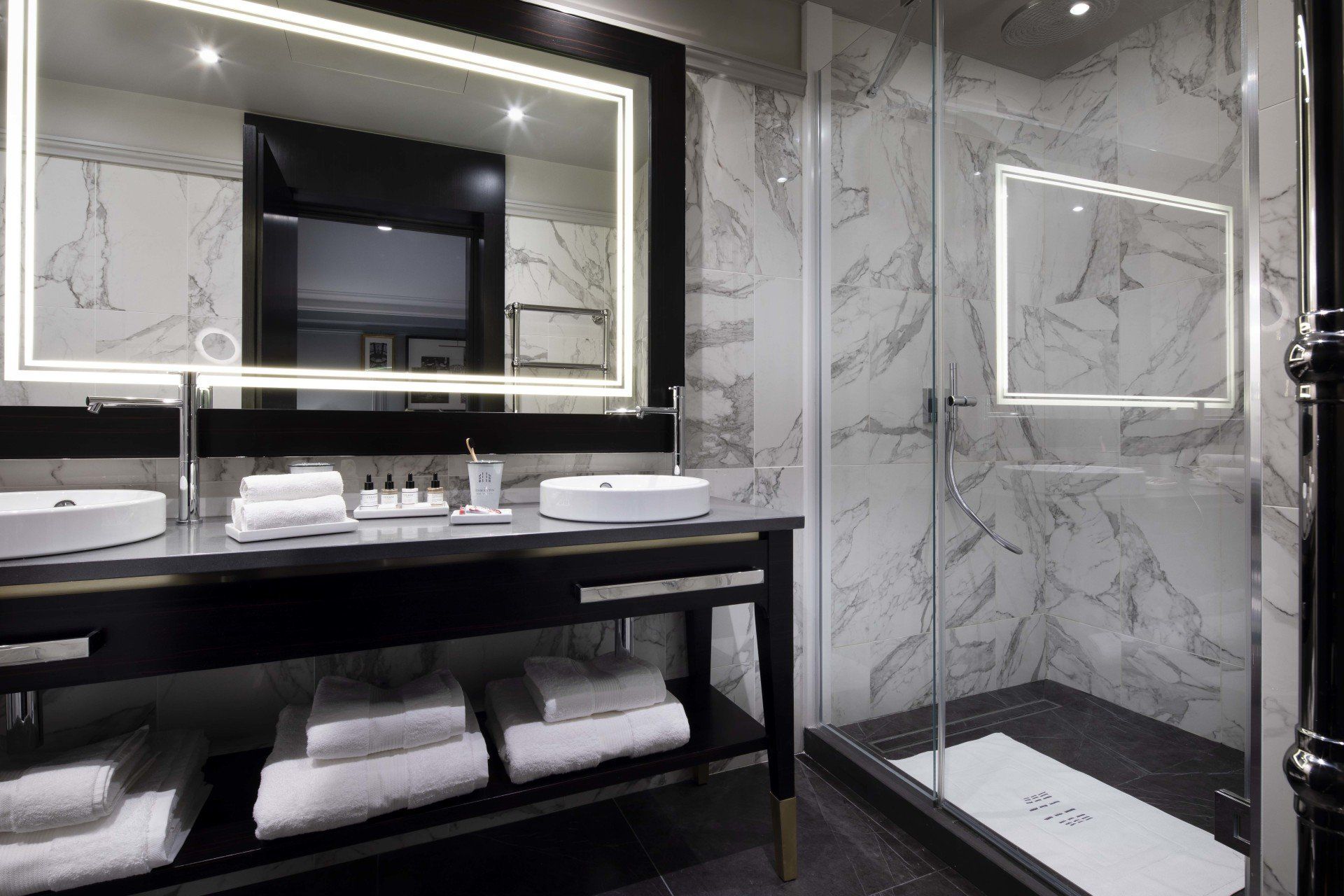 Une salle de bain avec deux vasques, un miroir et une douche à l'italienne.