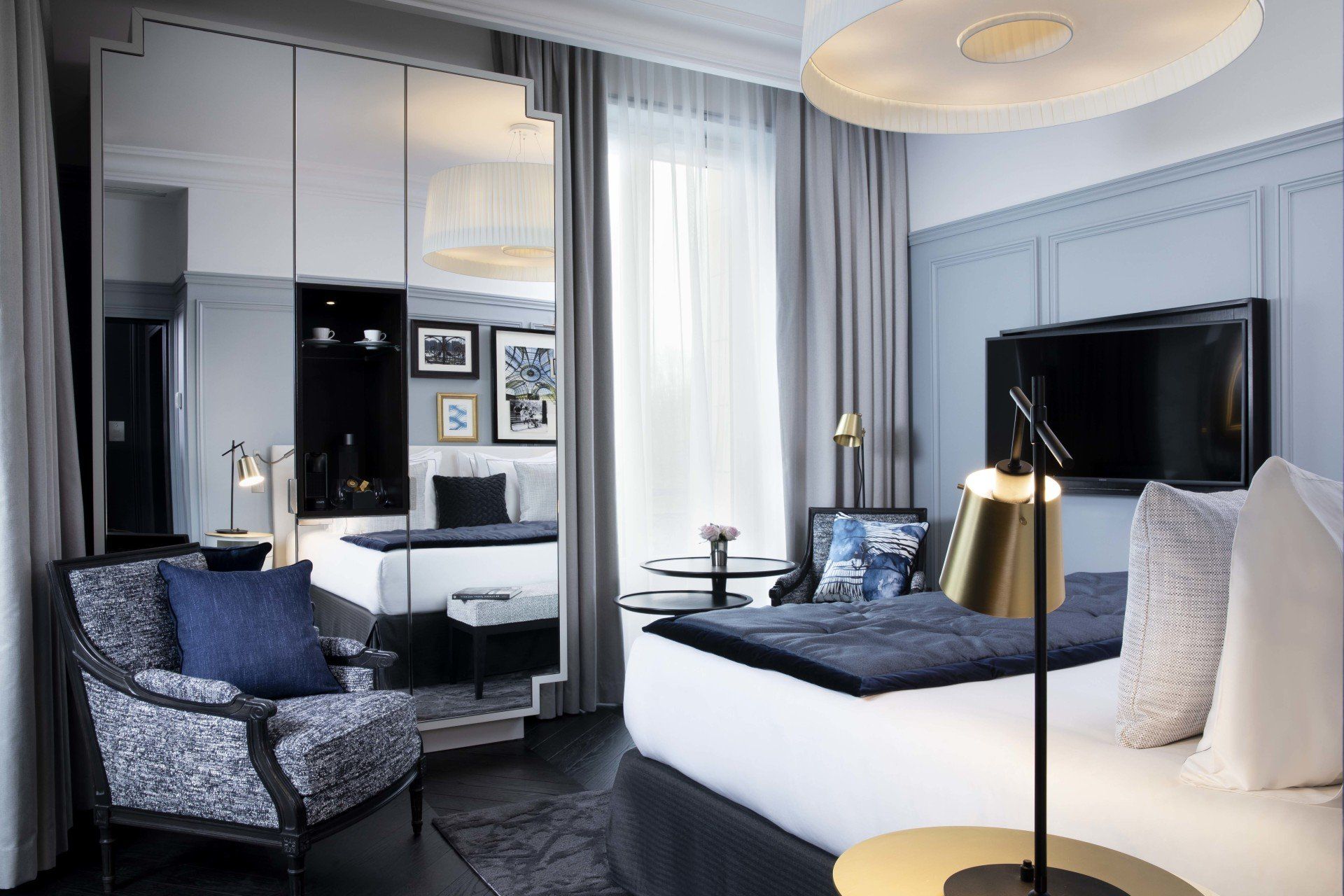 Une chambre d'hôtel avec un lit, une chaise, une lampe et une télévision.