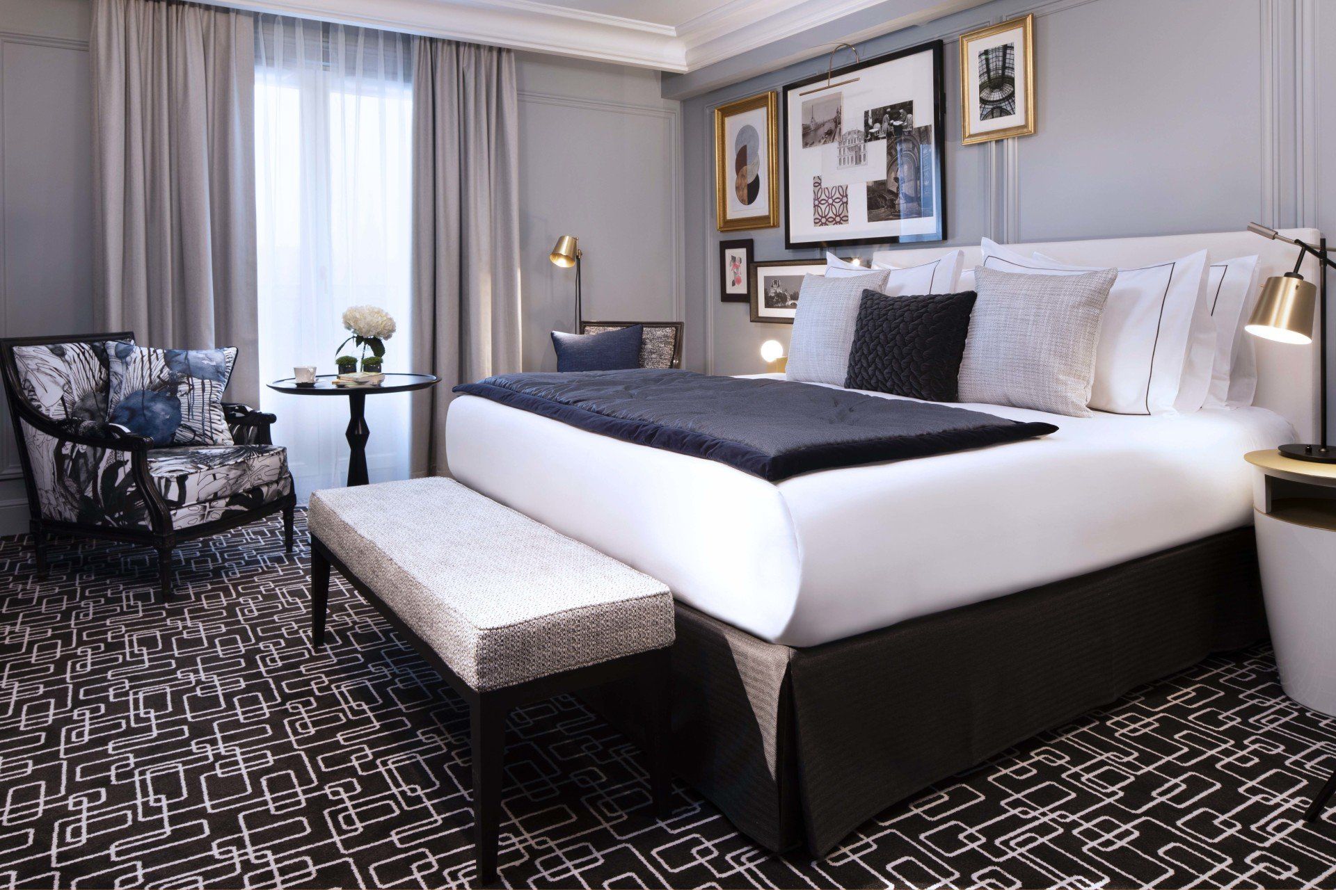 Une chambre d'hôtel avec un grand lit, une chaise, une table et un banc.