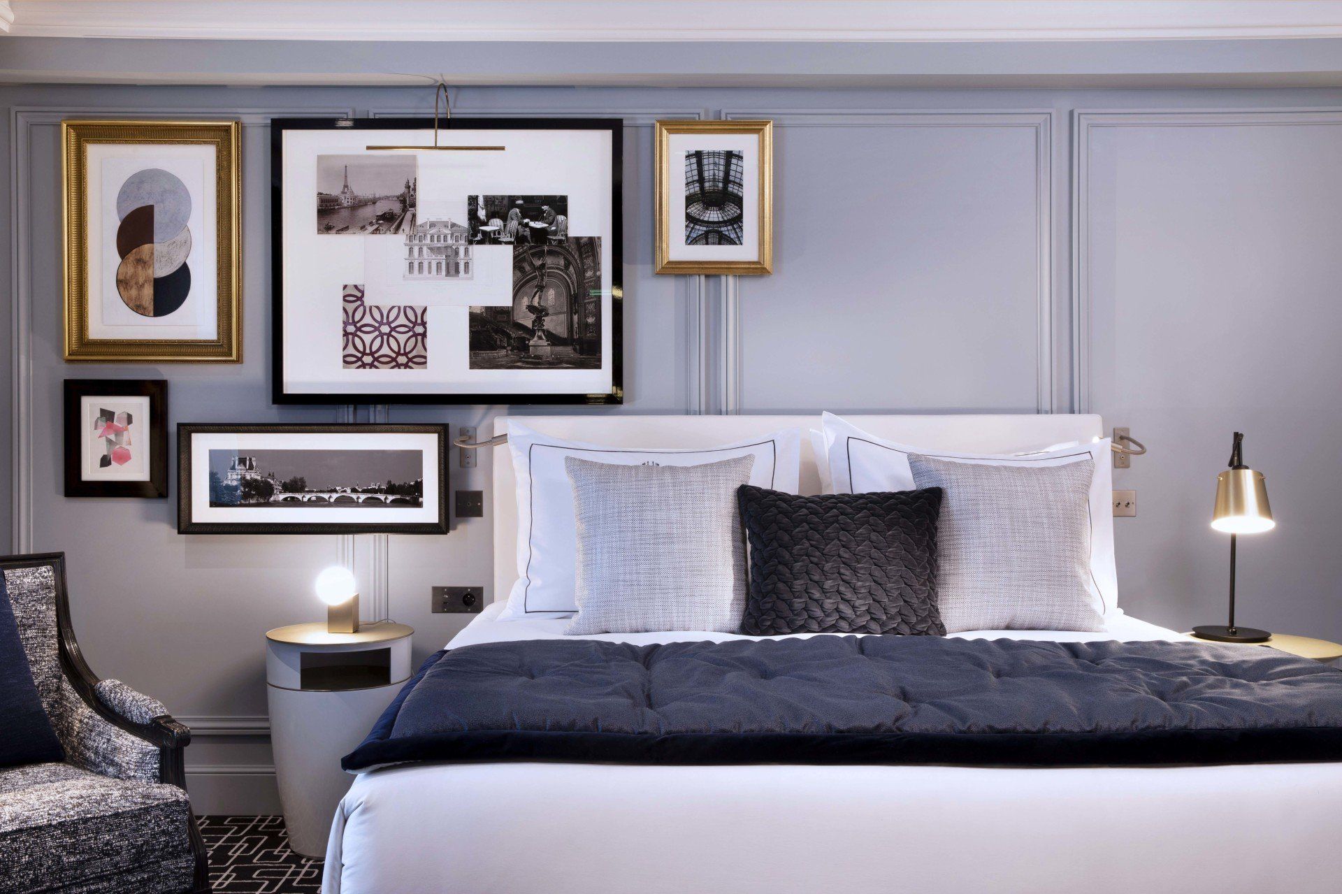 Une chambre avec un lit, une chaise, une table de nuit et des tableaux au mur.