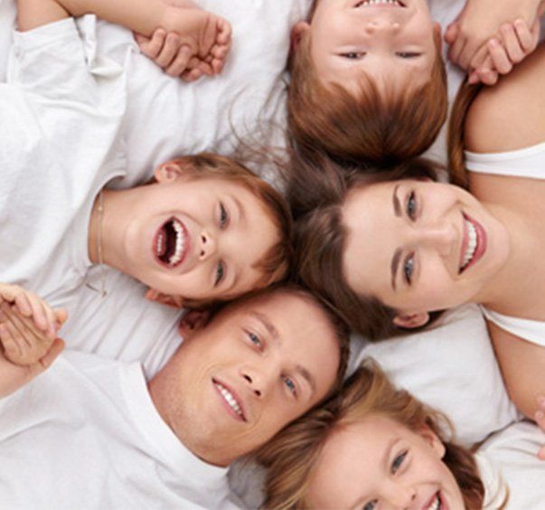 Un groupe de personnes sont allongées en cercle sur un lit et sourient.