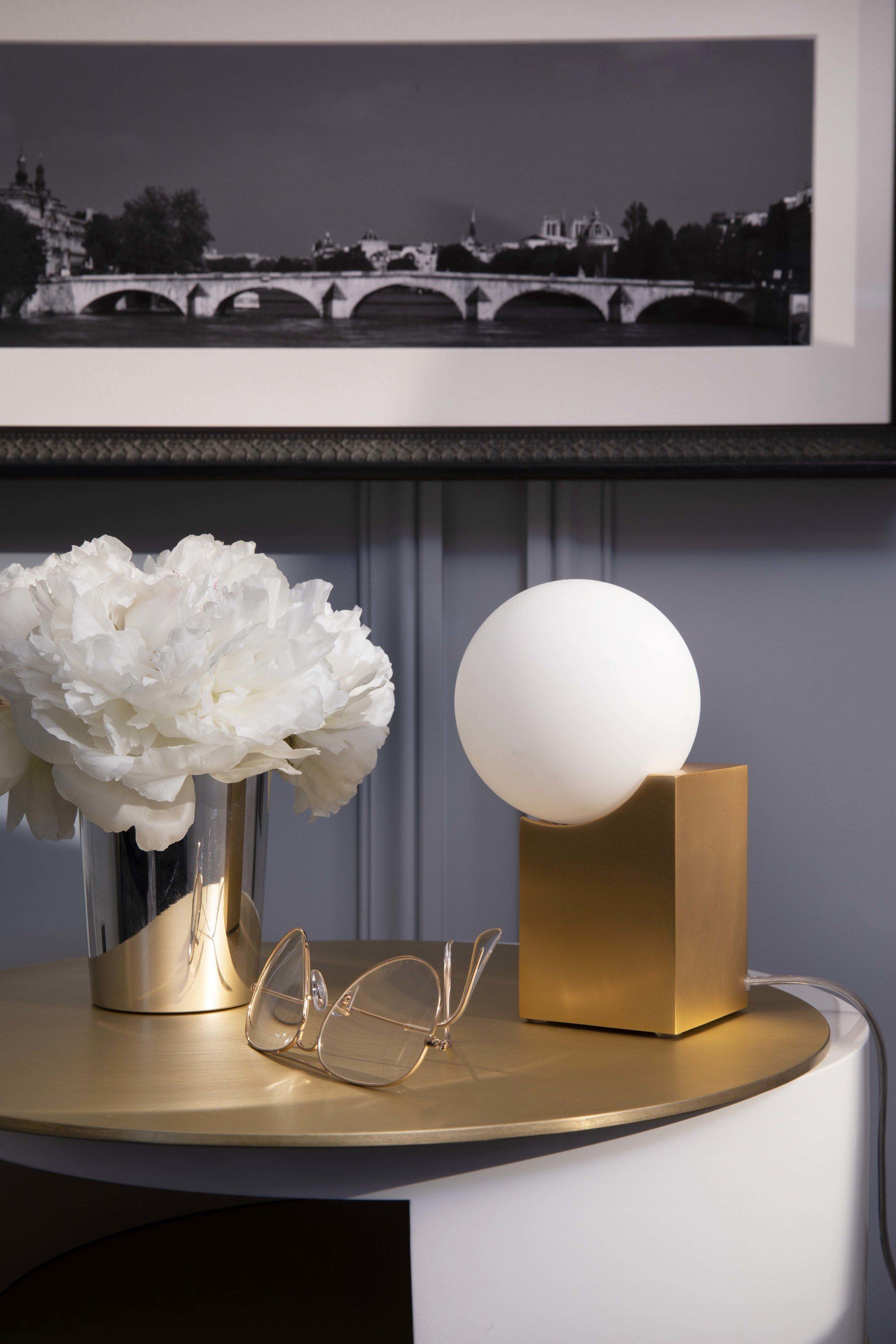 Une table avec un vase de fleurs et une lampe dessus