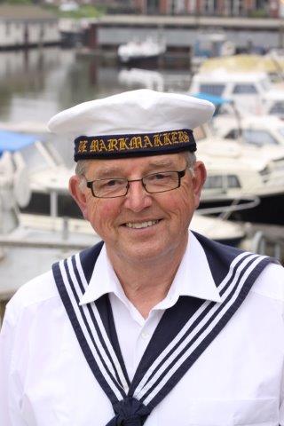 A smiling person wearing a white sailor uniform and cap with the text 