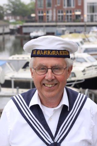 A smiling person wears a white sailor hat with 