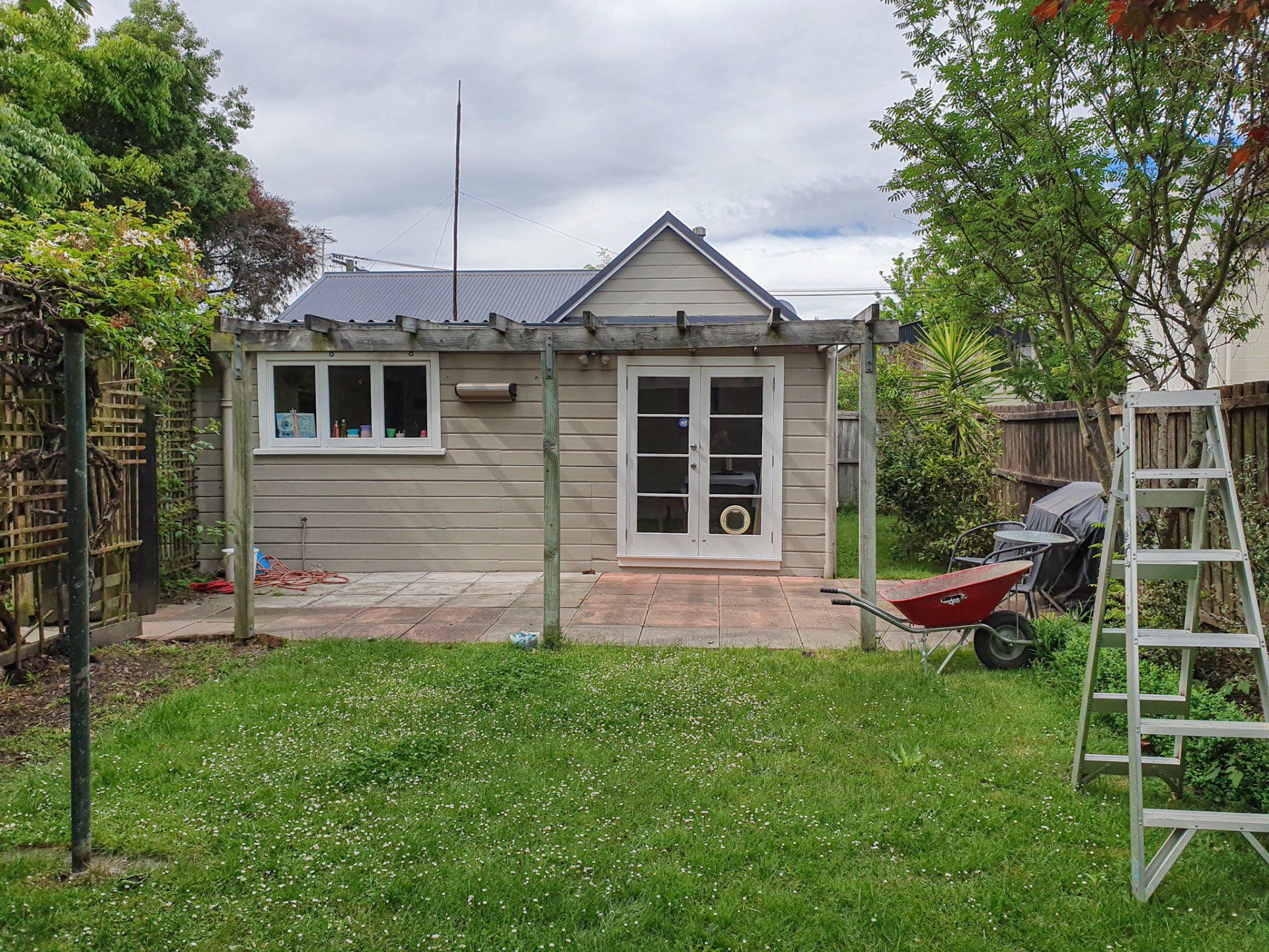 A small house is sitting in the middle of a lush green backyard.