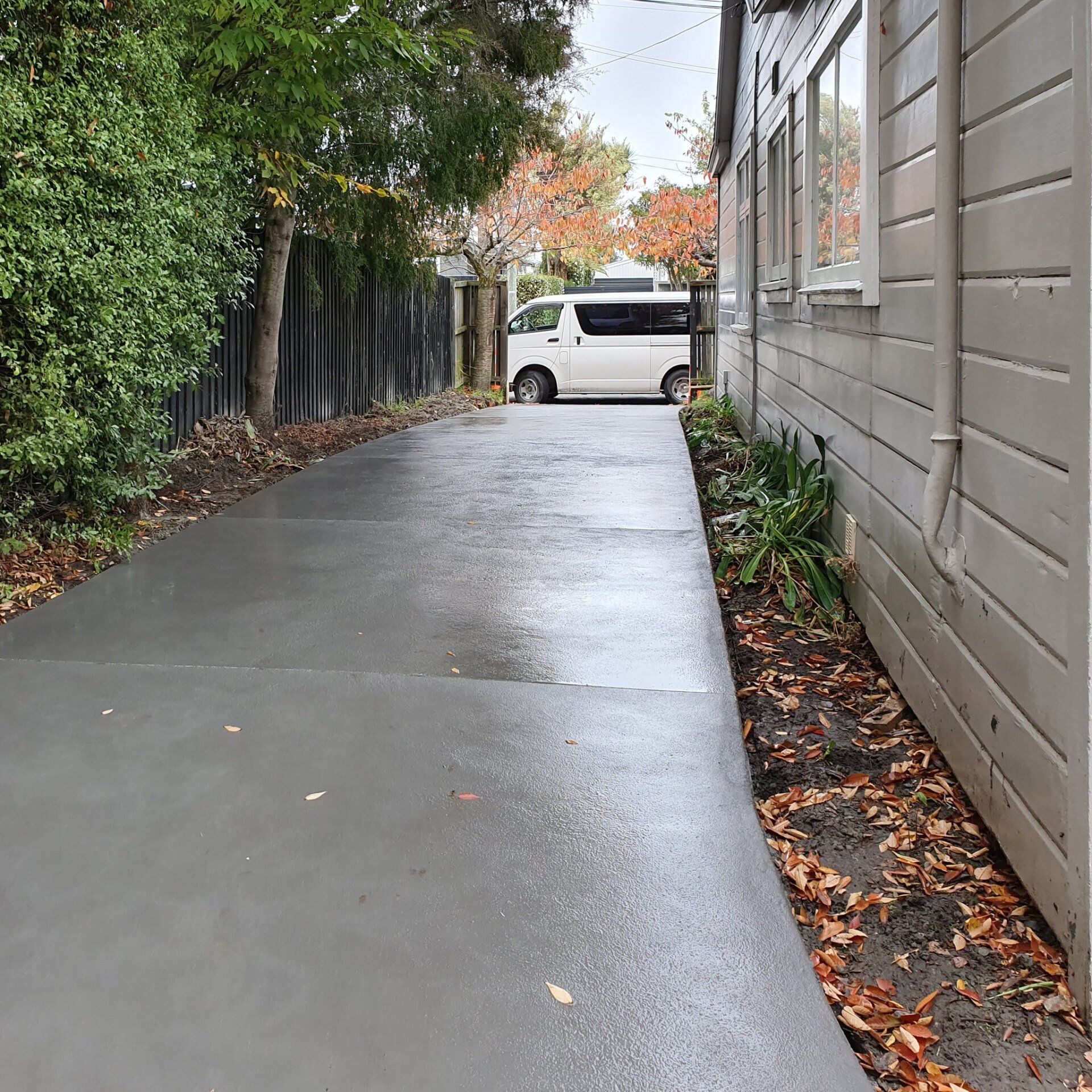 A white van is parked in a driveway next to a house