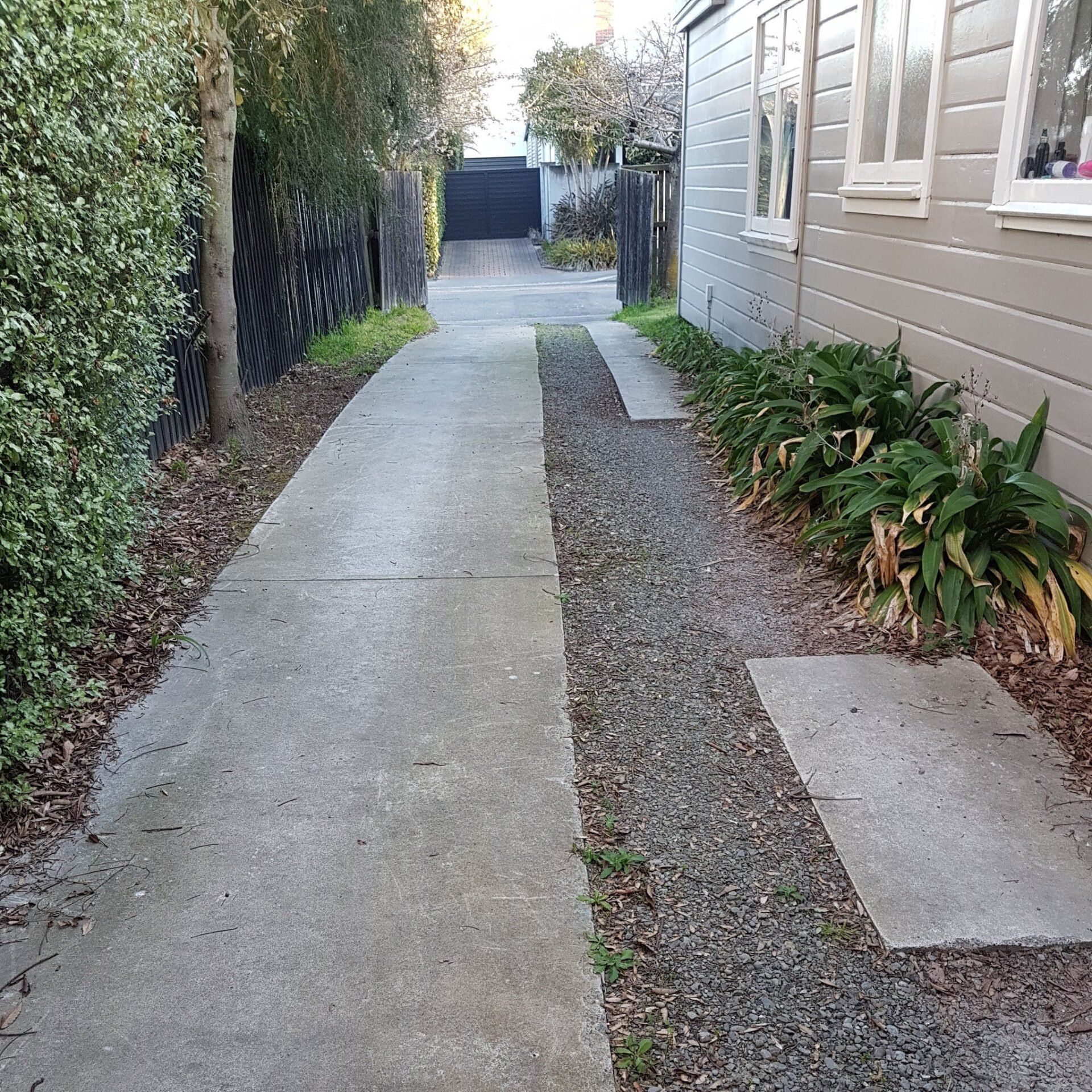 A sidewalk leading to a house with a gravel path.