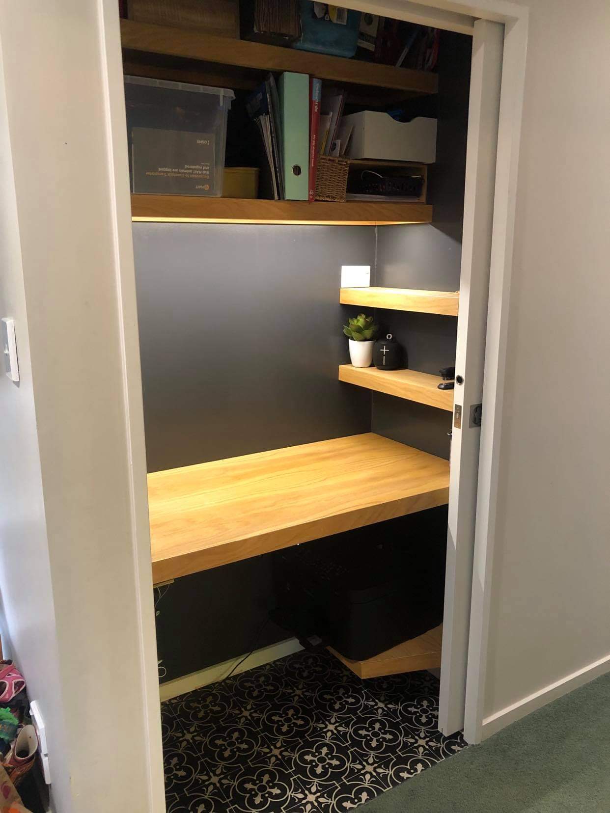A closet with a wooden desk and shelves in it.