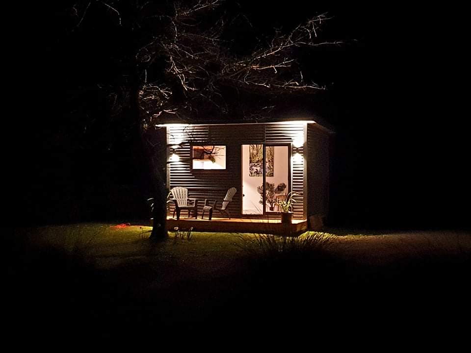 A small house is lit up at night in the woods.