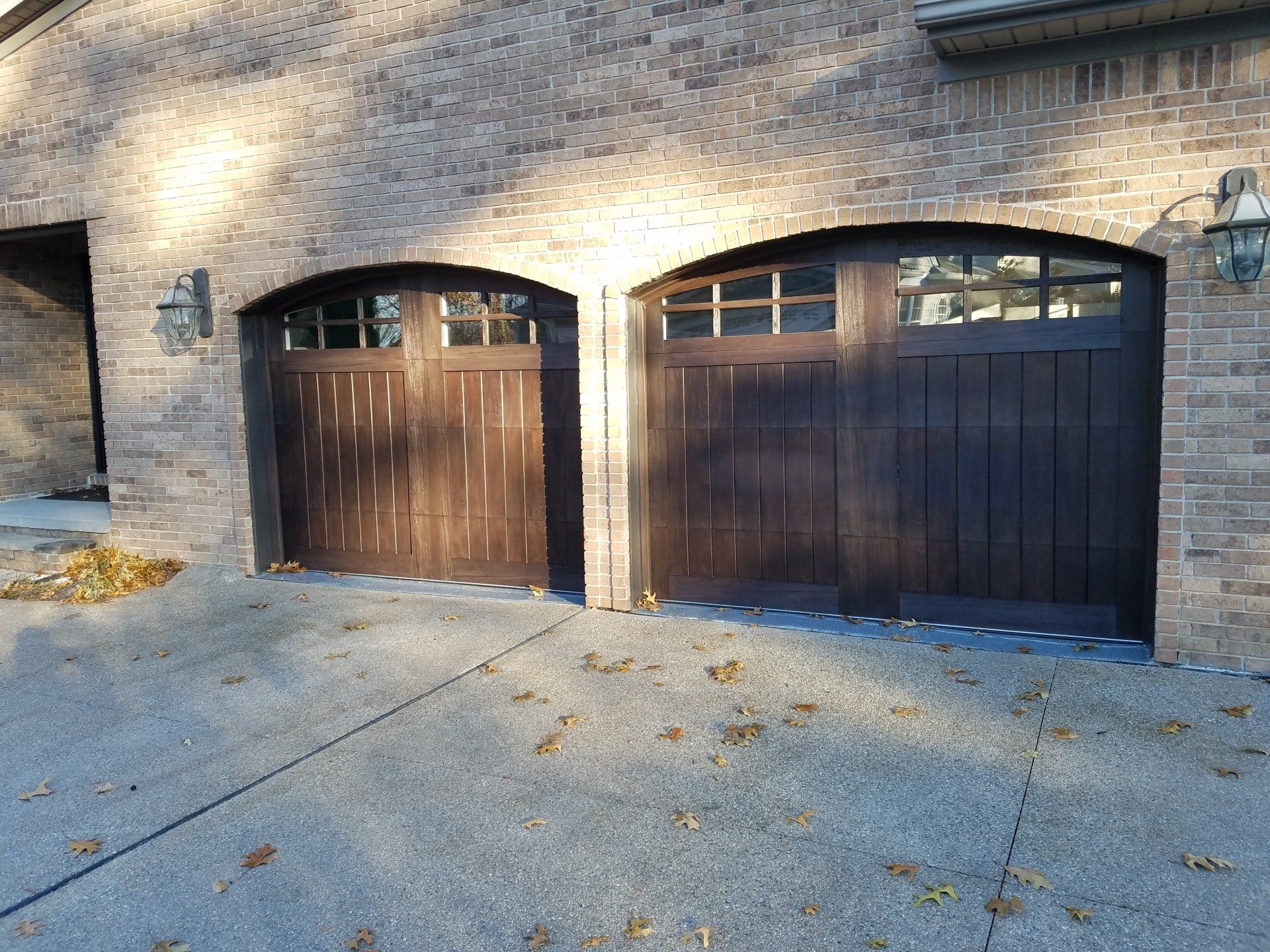 There are two garage doors on the side of a brick building.