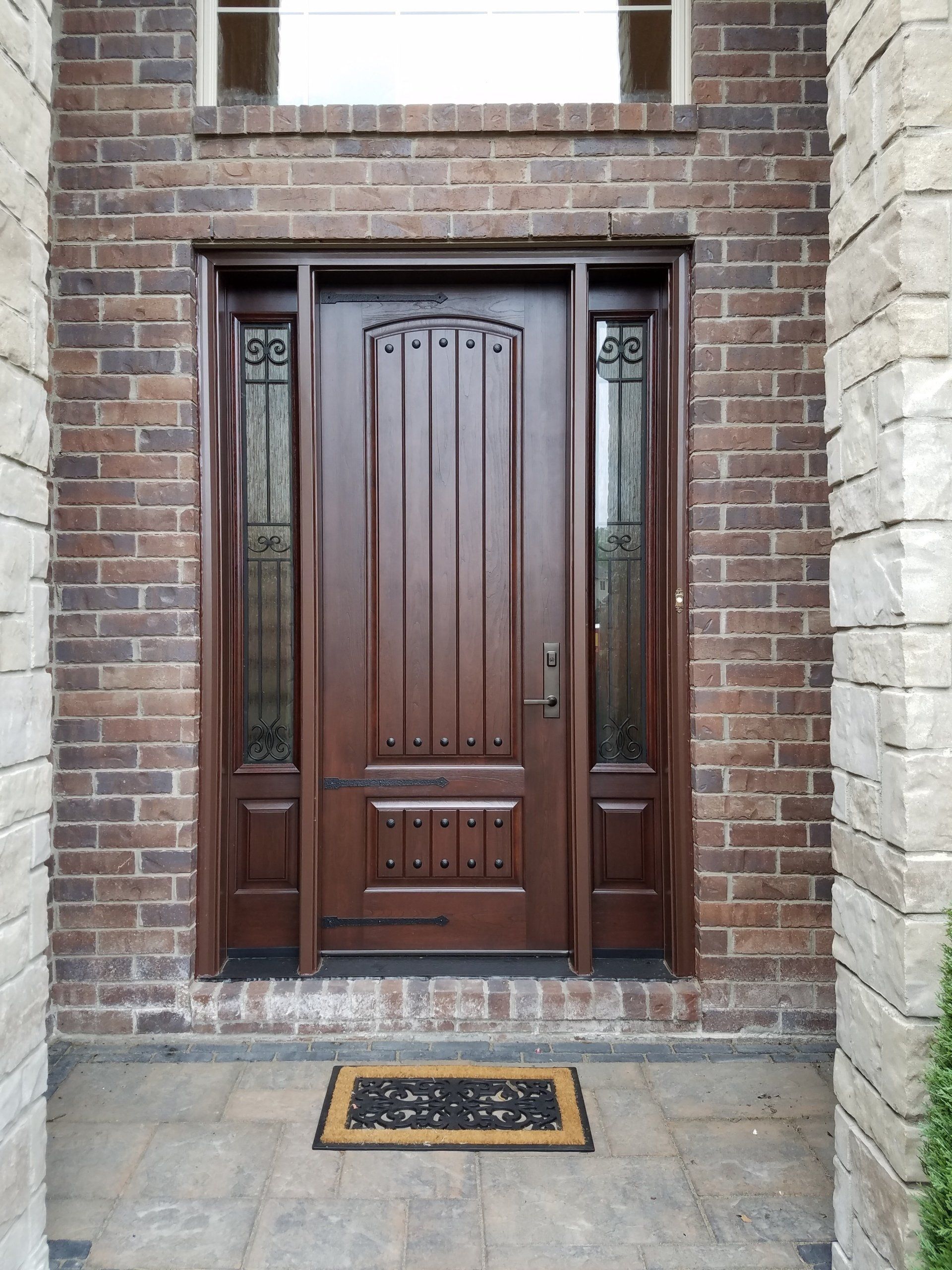 A brick building with a wooden door and a door mat