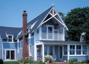 A blue and white house with a balcony and a chimney