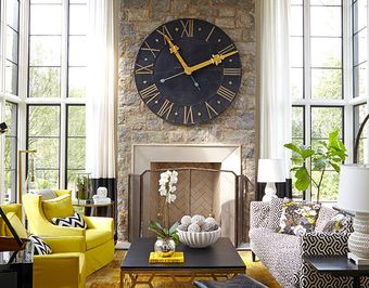 A living room with a fireplace and a large clock on the wall.