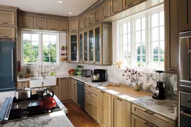 A kitchen with stainless steel appliances , wooden cabinets , marble counter tops and a large window.