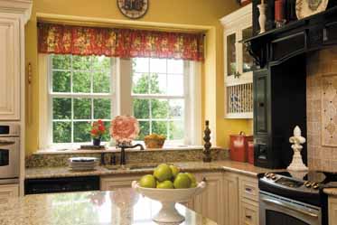 A kitchen with a bowl of apples on the counter and a window.