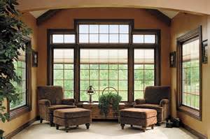A living room with chairs and ottomans in front of a large window.
