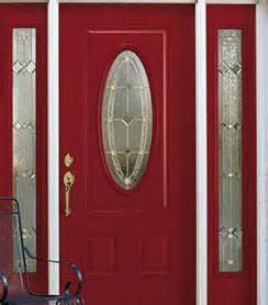 A red door with a stained glass window and a chair in front of it.