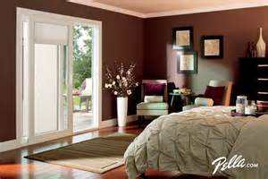 A bedroom with a bed , chair , dresser and sliding glass doors.