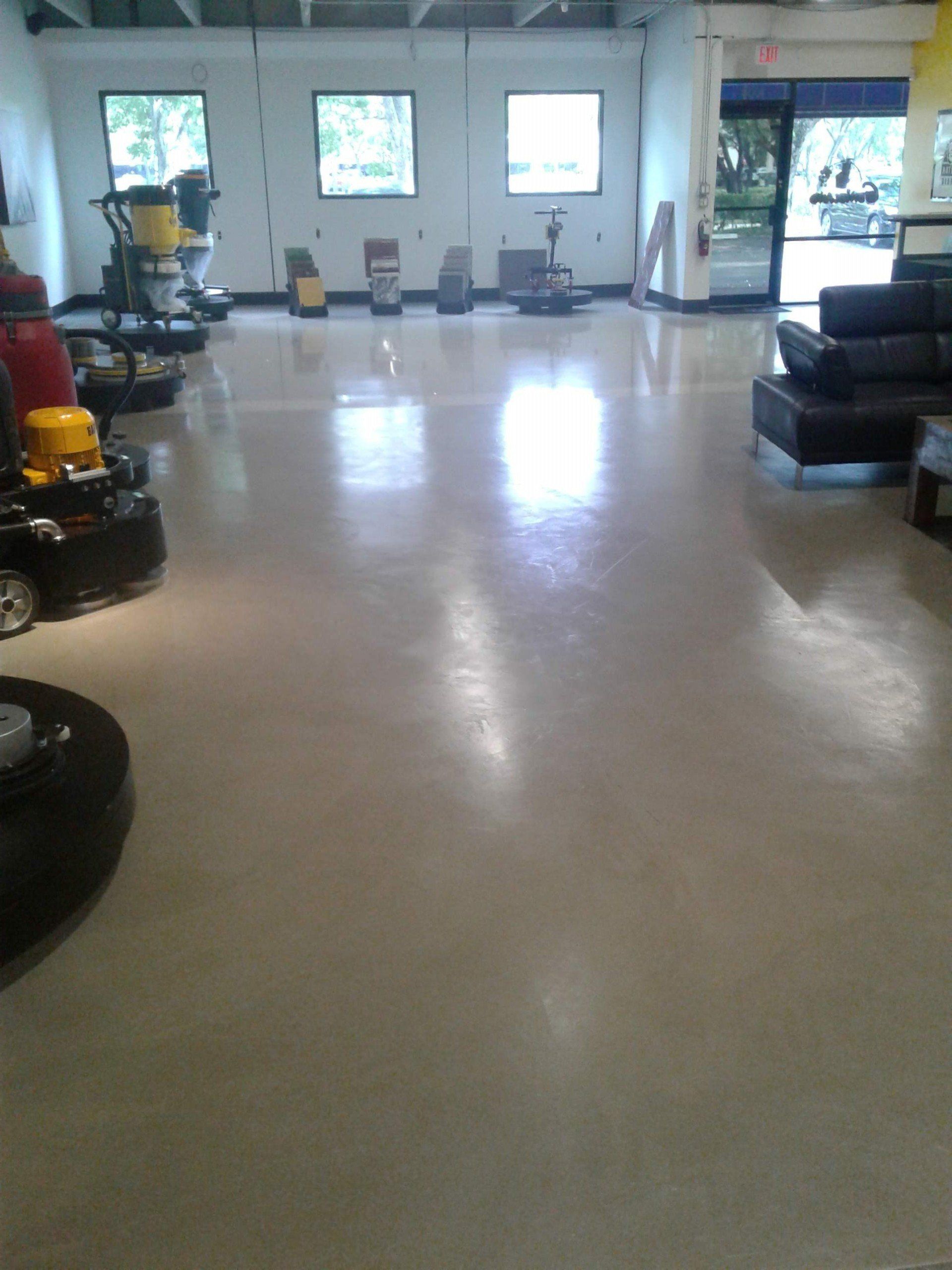 Spacious lobby with polished floor, windows, chairs, and a black leather couch.