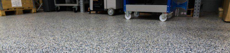 Low-angle view of a speckled floor beneath equipment carts in a workshop or storage area