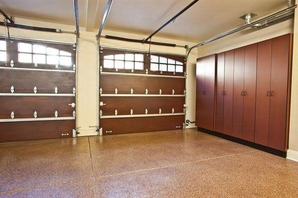 Empty garage with brown storage cabinets, white shelves, and a speckled floor