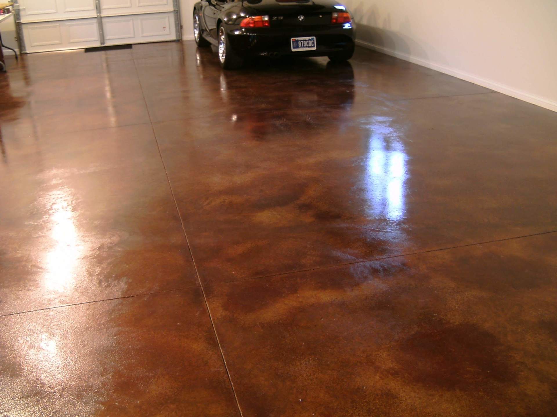 Glossy stained concrete garage floor with a black car parked at the back