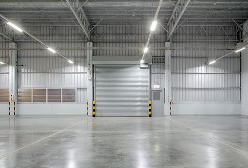 An empty warehouse with a sliding door and a concrete floor.