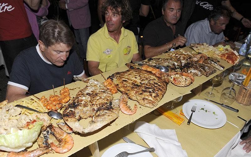 delle persone vicino a una tavolata di pesce misto