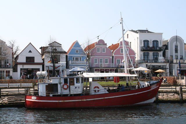 Ein rotes Boot liegt vor einer Reihe bunter Häuser