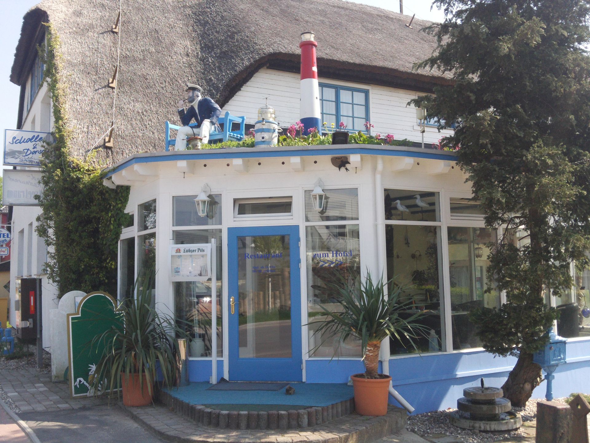 Ein weißes Gebäude mit einem Strohdach und einer blauen Tür