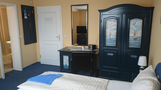 Ein Schlafzimmer mit Bett, Kleiderschrank, Schreibtisch und Spiegel.