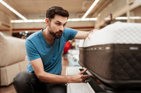 Man Testing a Mattress in Furniture Store — Danville, KY — Mattresses & More Man Testing a Mattress in Furniture Store — Danville, KY — Mattresses & More