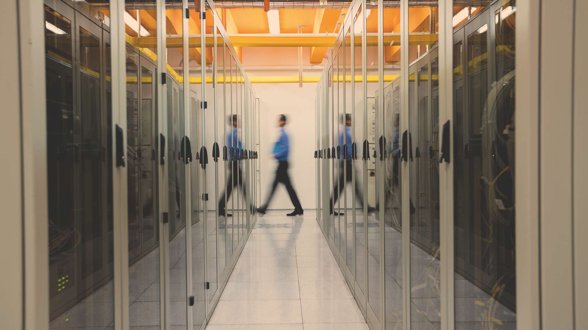 Um grupo de pessoas caminha por uma sala de servidores em um data center.