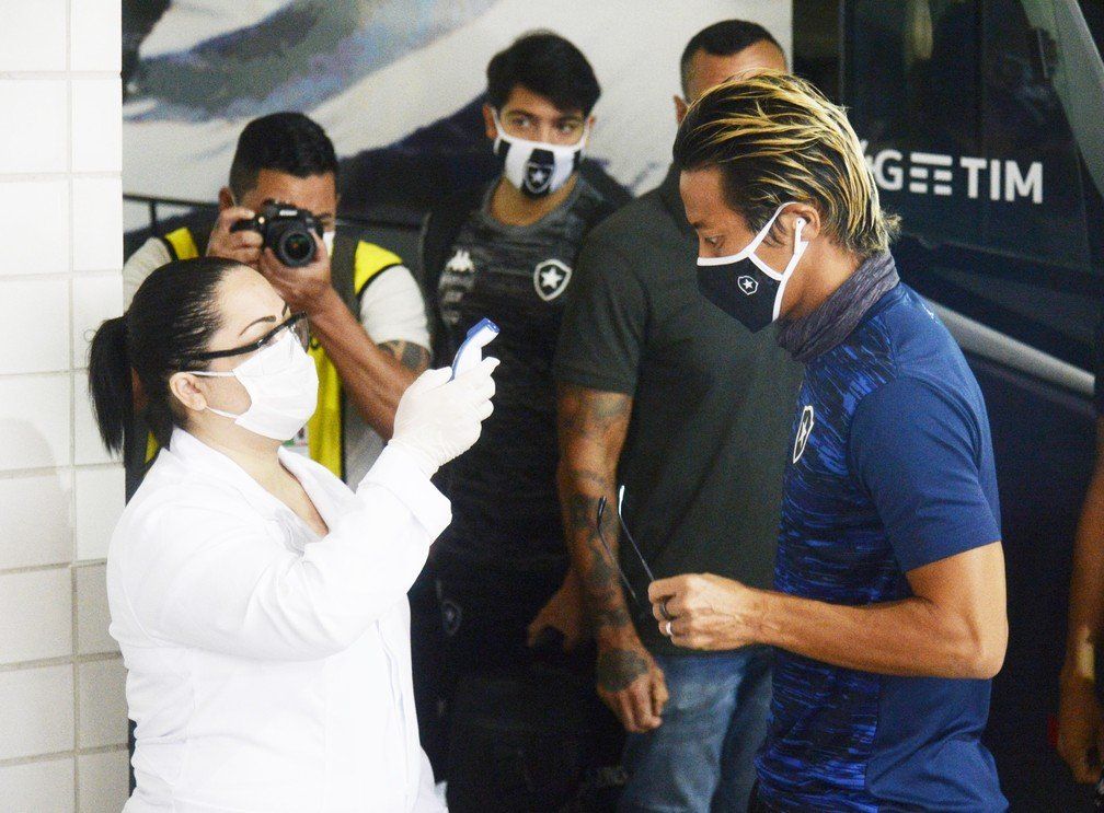 Um grupo de pessoas usando máscaras e luvas está parado na frente de uma van que diz getim