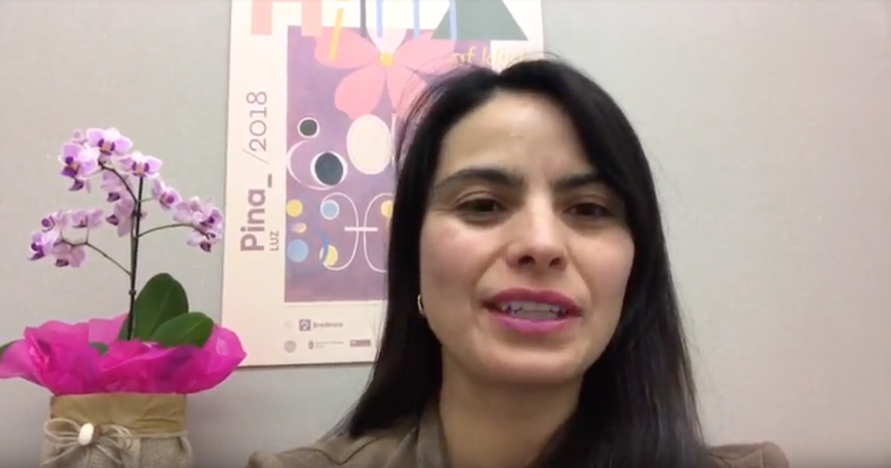 Uma mulher está diante de um vaso de flores.