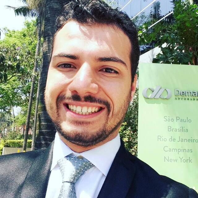 Um homem de terno e gravata sorri na frente de uma placa que diz odontologia