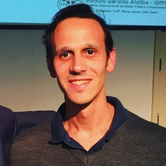Um homem sorri diante de uma placa que diz instituto geraldo algiba