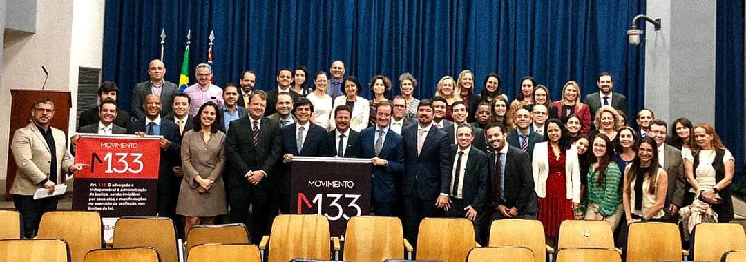 Um grande grupo de pessoas posa para uma foto em frente a um pódio com o número 133.
