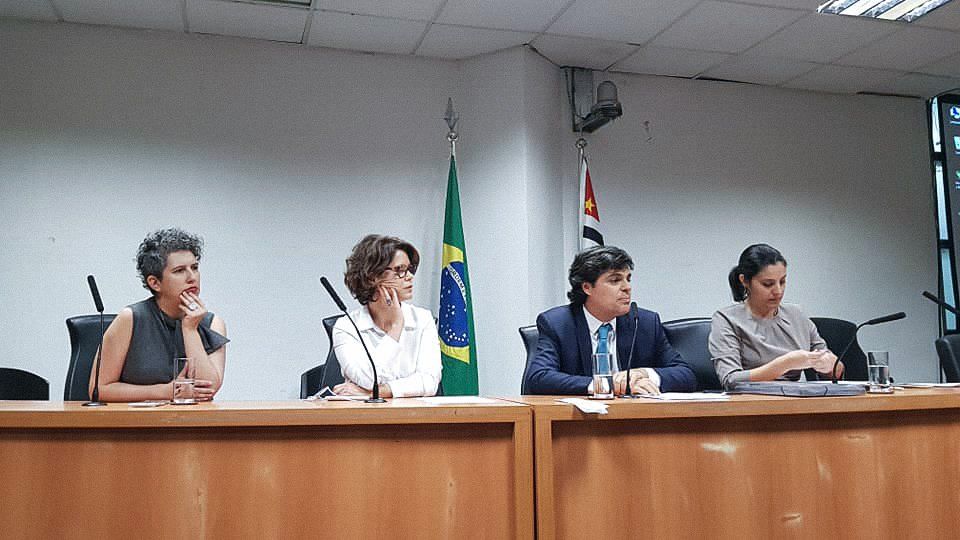 Um grupo de pessoas está sentado à mesa em uma sala de conferências.