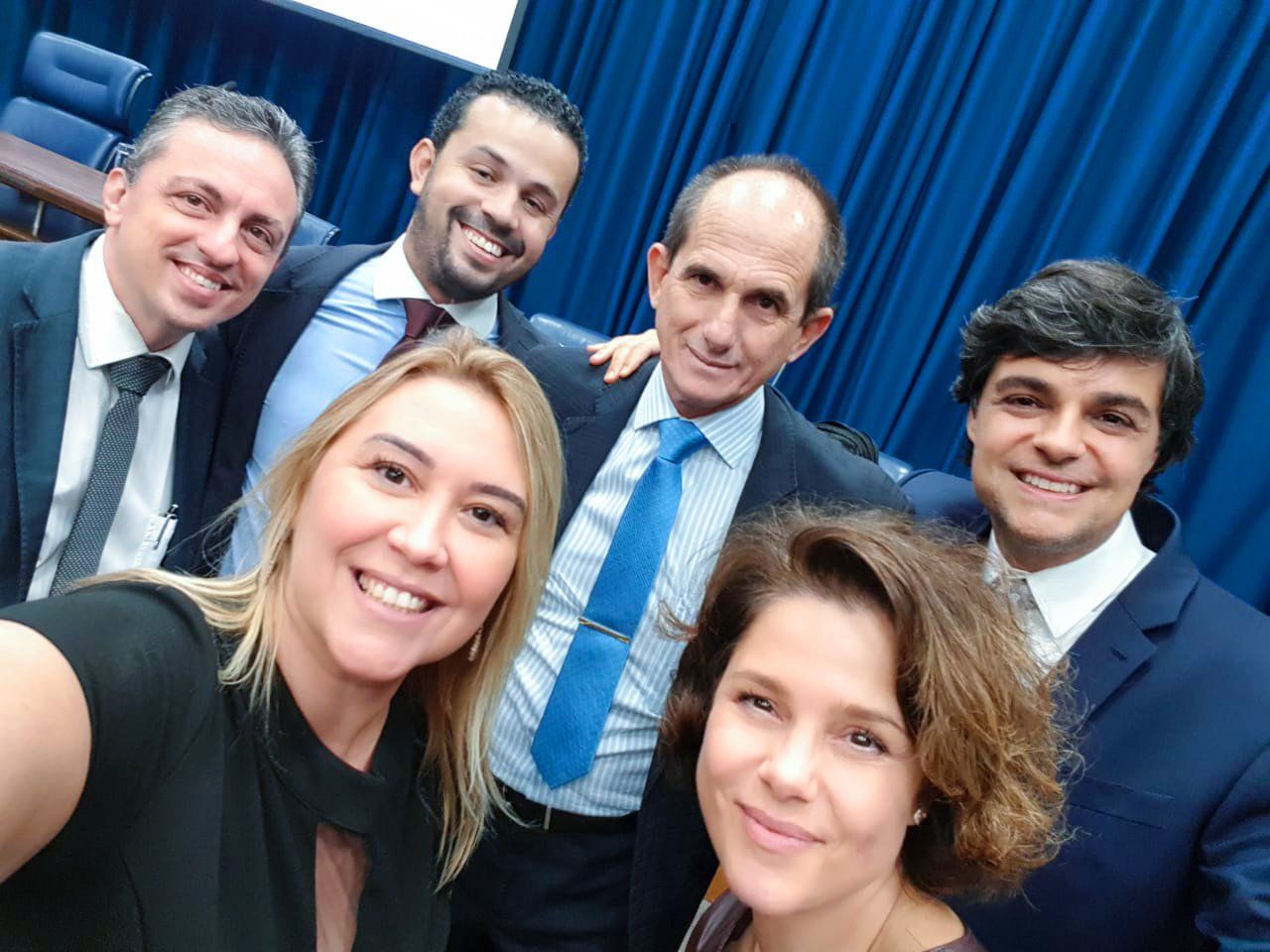 Um grupo de pessoas posando para uma foto em frente a uma cortina azul
