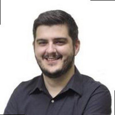 Um homem com barba está sorrindo e vestindo uma camisa preta.