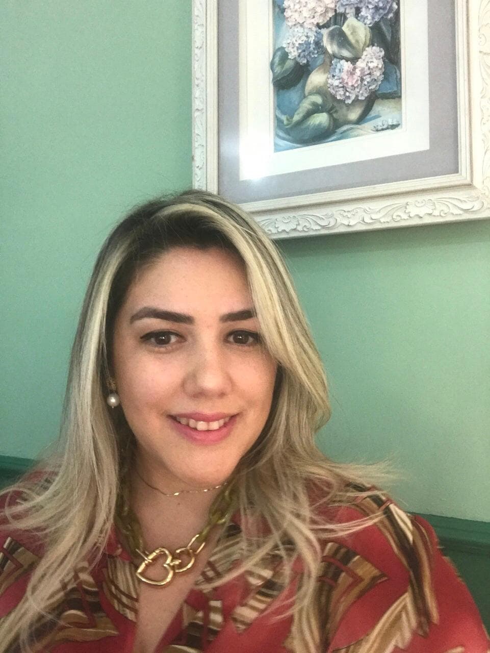Uma mulher sorri diante de uma pintura na parede.
