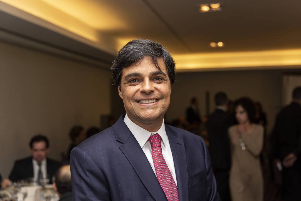 Um homem de terno e gravata está sorrindo para a câmera.